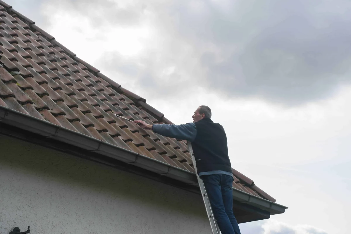 A roofer working at the edge of a tiled roof